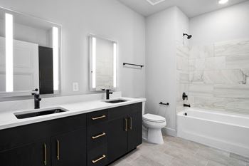 A bathroom with black cabinets and a white bathtub